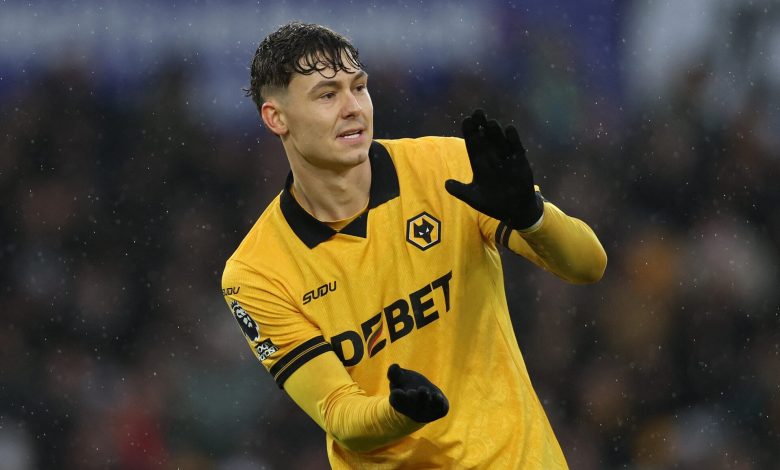 Football player celebrating victory in rain, wearing yellow jersey with sponsor logos, during match.
