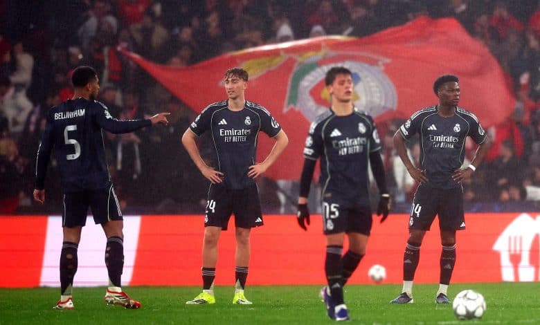 Football players in black jerseys celebrating on the field with a large flag in the background.